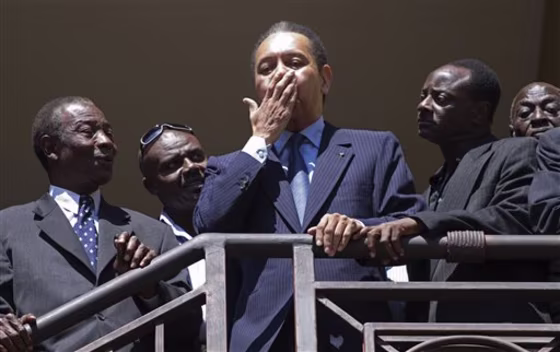 Haiti's former dictator Jean-Claude 'Baby Doc' Duvalier, center, gestures to supporters on the balcony of his hotel room in Port-au-Prince, Haiti, on Wednesday.